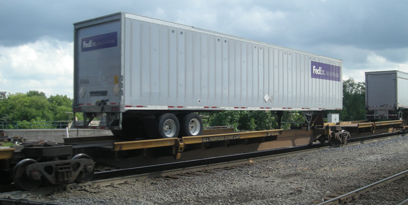 FIGURE 6. Traditional Trailer-on-Flatcar
This image shows a full-sized semi-trailer being carried on the top of a railway flatcar.
